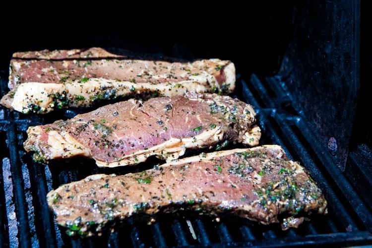 marinated steaks on open grill